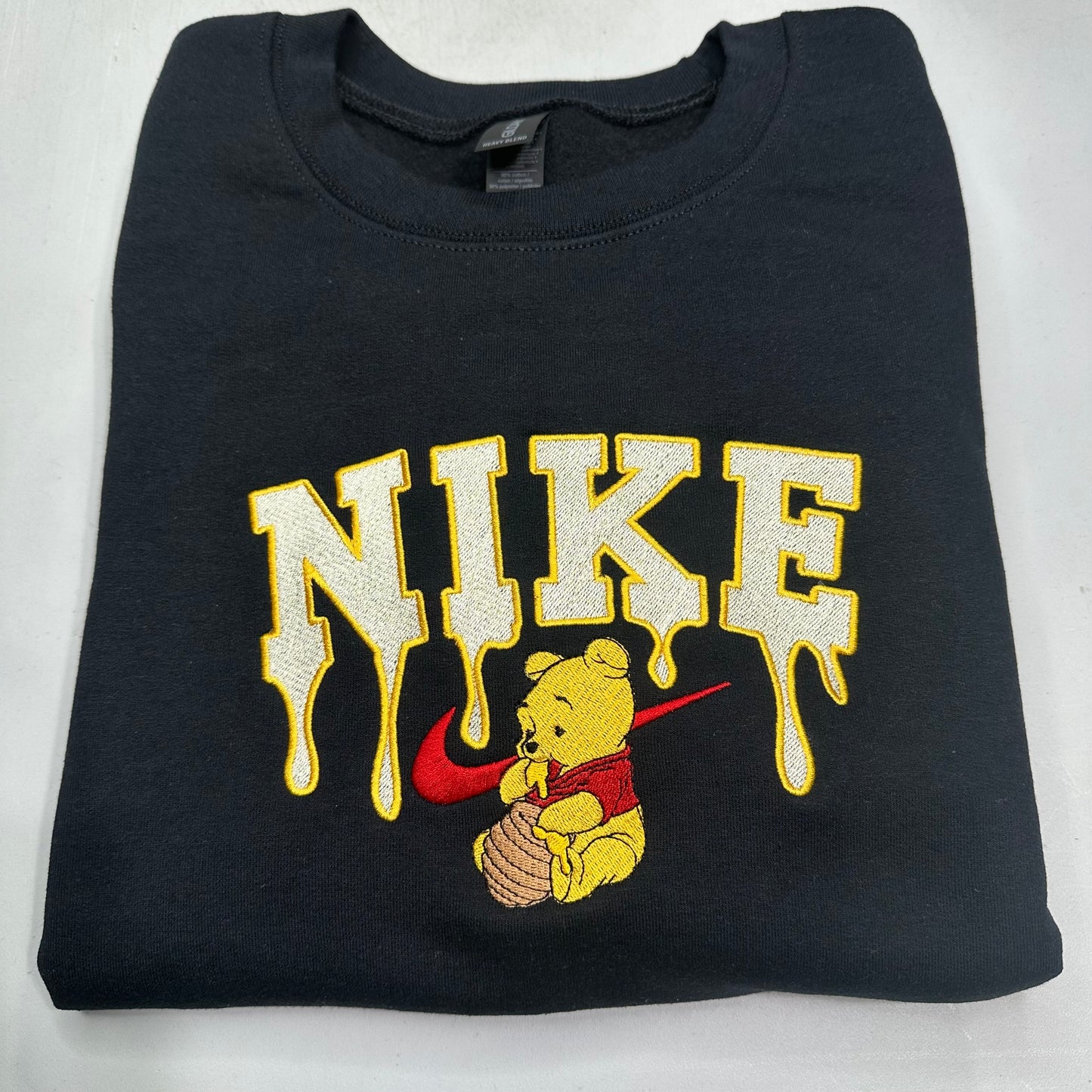 black sweatshirt with embroidered winnie the pooh with honey dripping from the nike logo