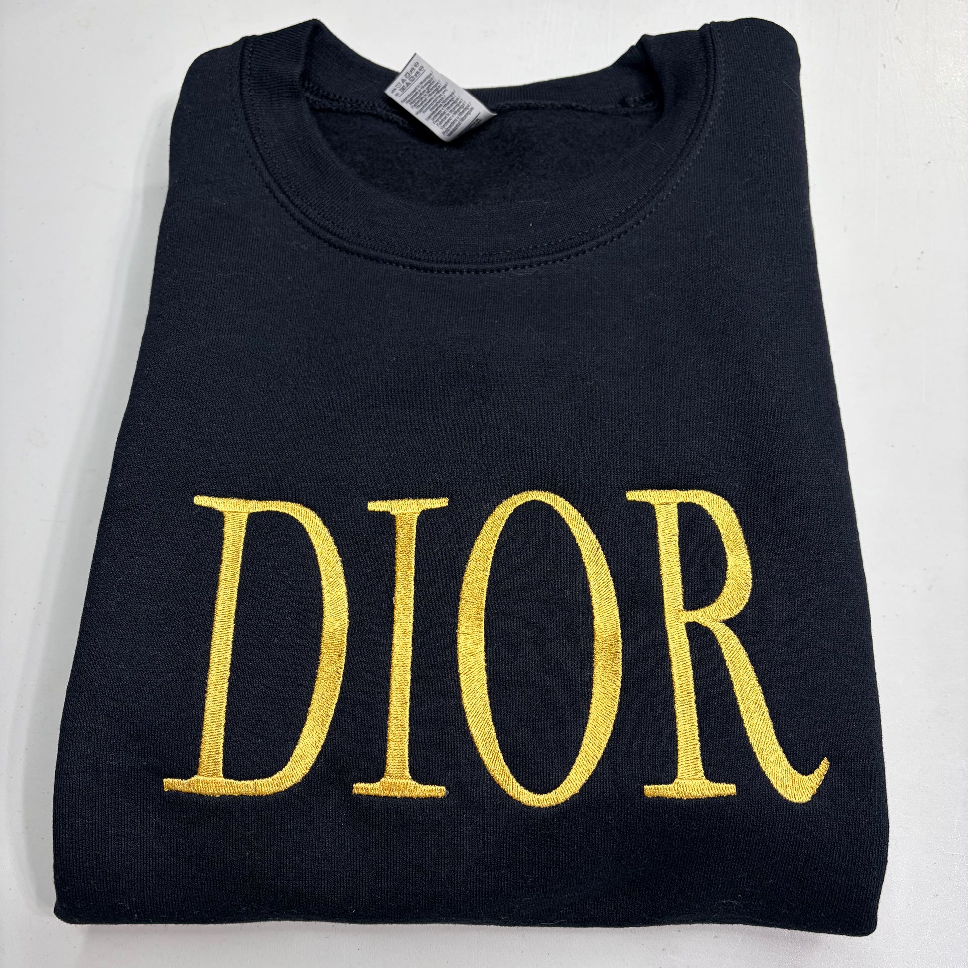 black sweatshirt with embroidered gold dior logo on it