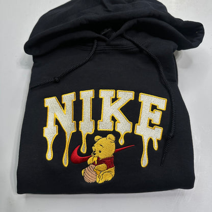 black sweatshirt with embroidered winnie the pooh with honey dripping from the nike logo