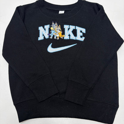 A black long-sleeve sweatshirt featuring a light blue 'NIKE' graphic with a cartoon bluey dog mascot and a light blue swoosh on the front.