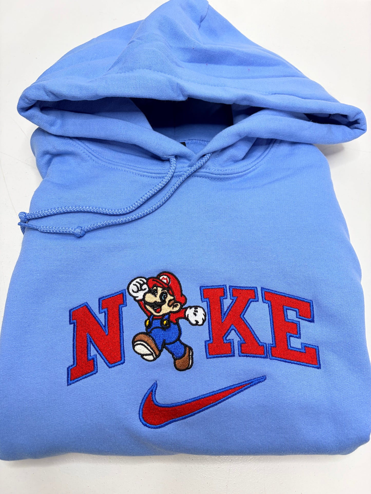 Blue hoodie with mario bros character design and 'NKE' text on a white background