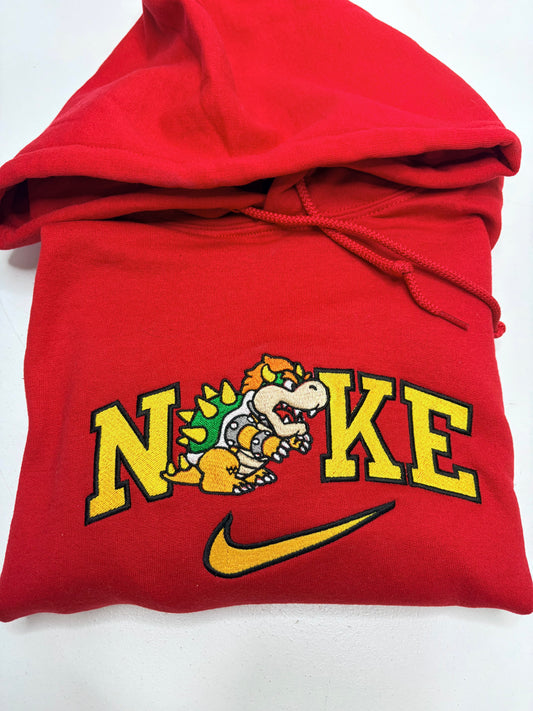 red hoodie with an embroidered design of bowser from mario bros in between the letters of the nike logo