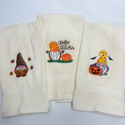 beige towels with embroidered fall gnome designs on them
