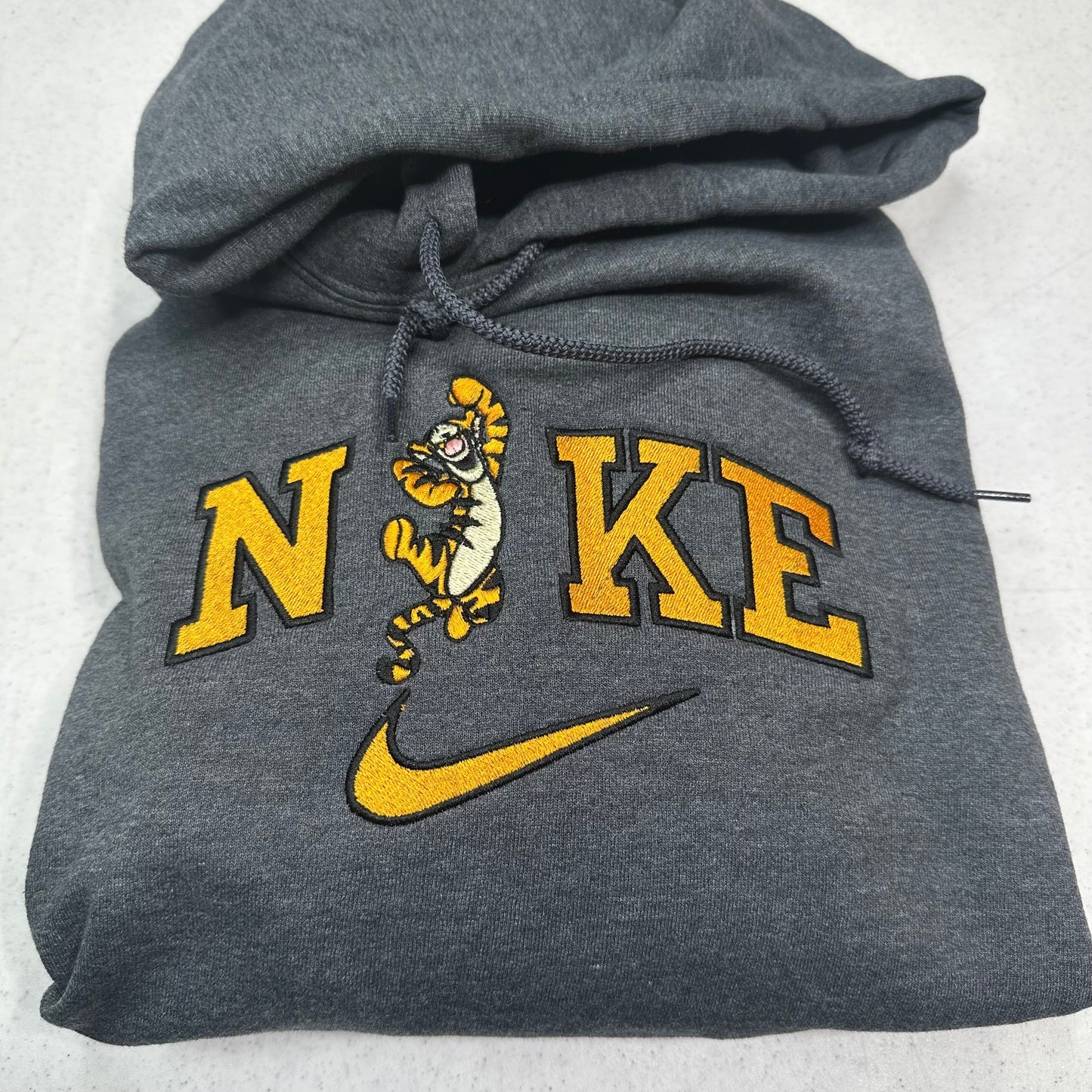 gray sweatshirt with embroidered tigger in the middle of the nike logo