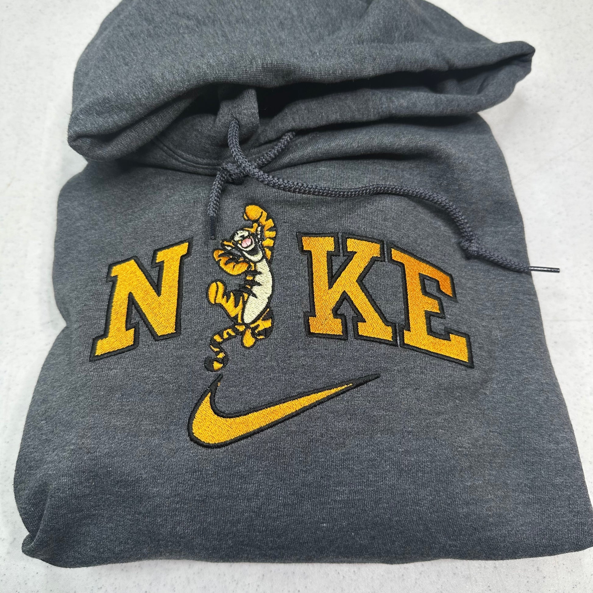 gray sweatshirt with embroidered tigger in the middle of the nike logo