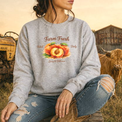 woman wearing gray sweatshirt with peaches graphic that says farm fresh picked daily