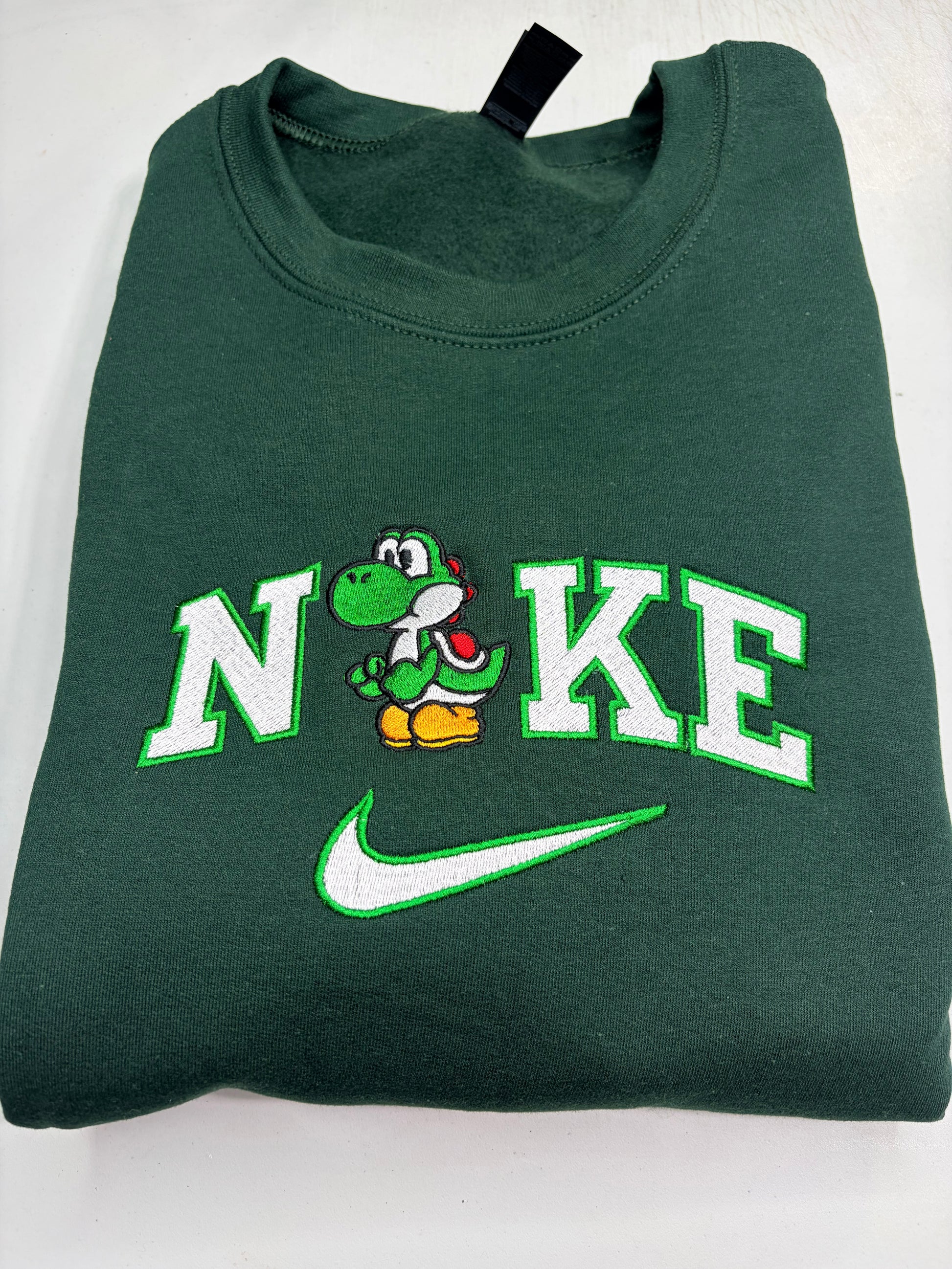 Green sweatshirt with embroidered mario bros yoshi design on a white background