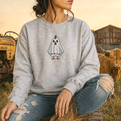 woman wearing a light gray sweatshirt with an embroidered halloween theme chicken with a ghost costume on