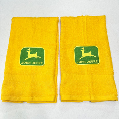 Two yellow towels with green John Deere logos, displayed side-by-side on a light gray background.