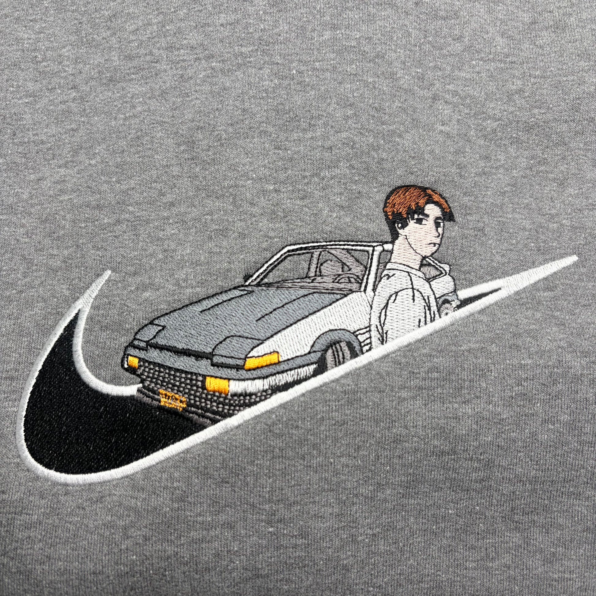 gray background with embroidered takumi and his AE86 car on it