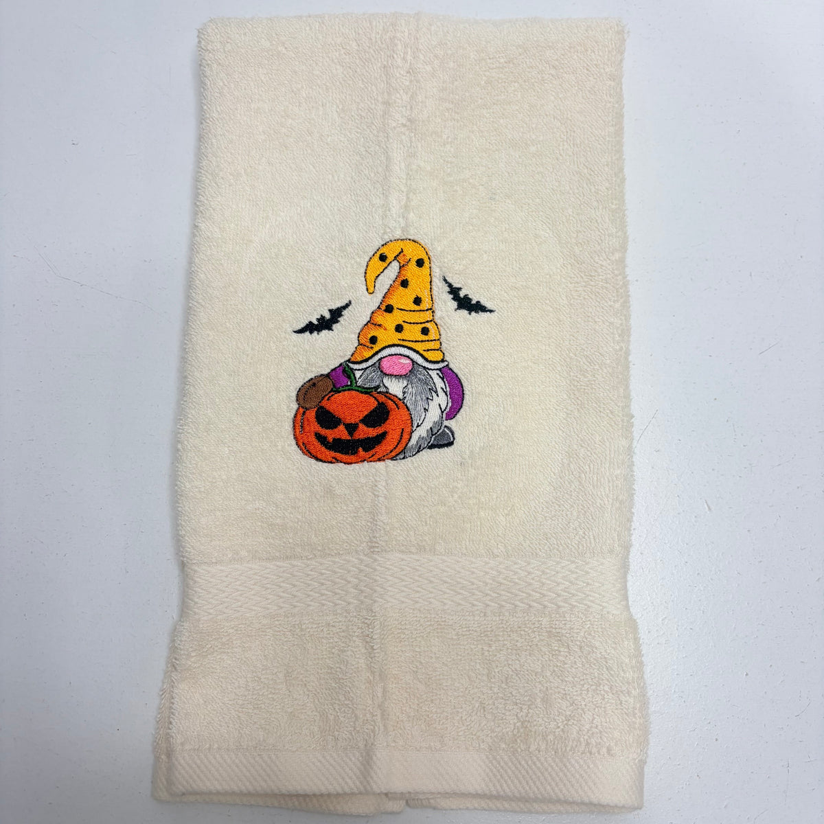 beige towel with an embroidered fall halloween gnome design on it