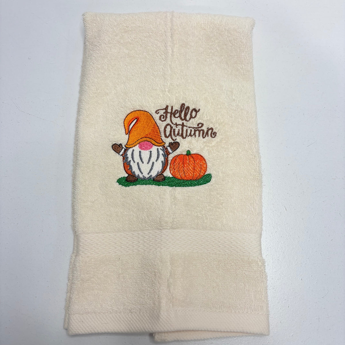 beige towel with an embroidered fall gnome design on it