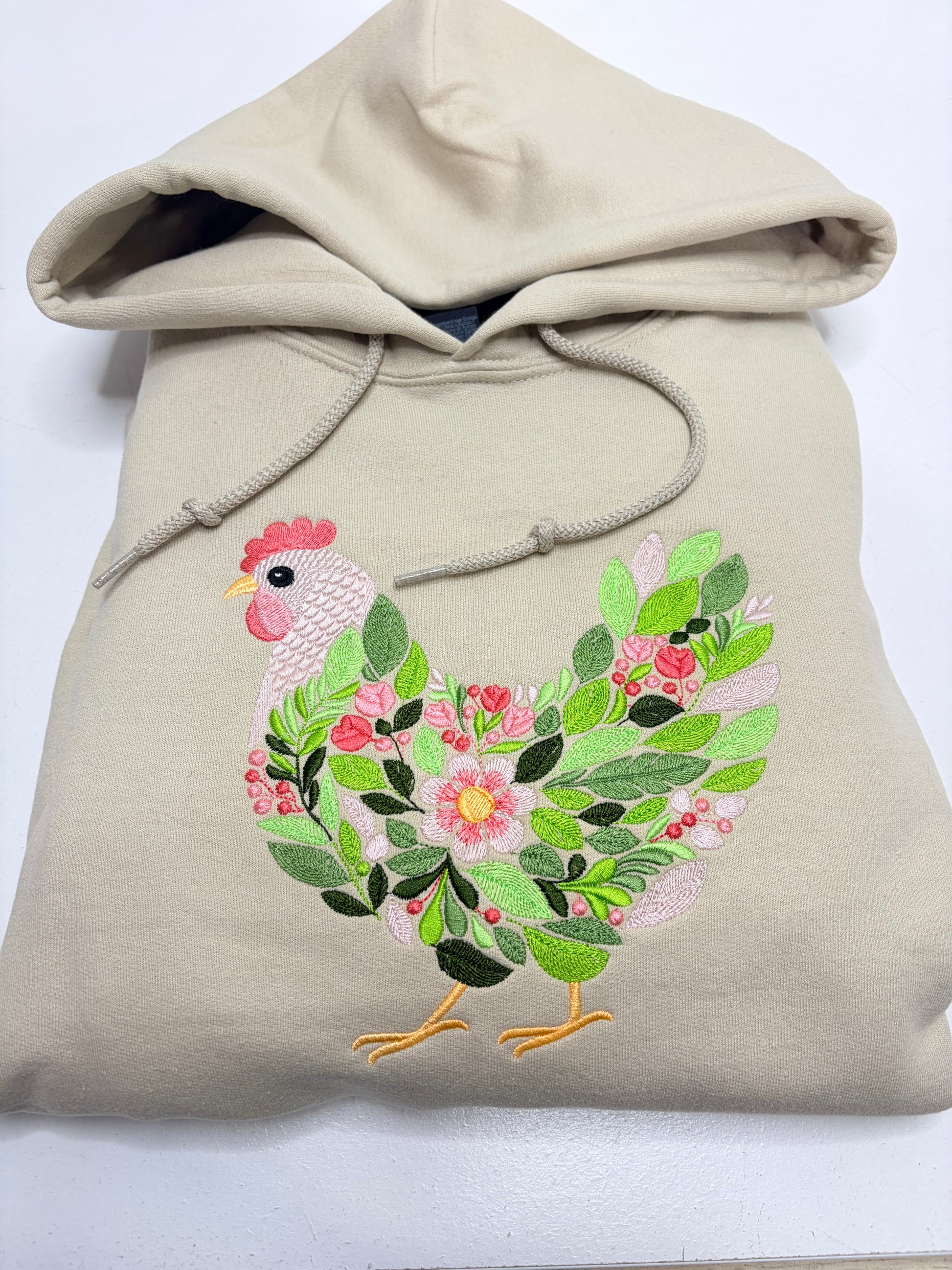 Beige hoodie with a floral chicken design on a white background