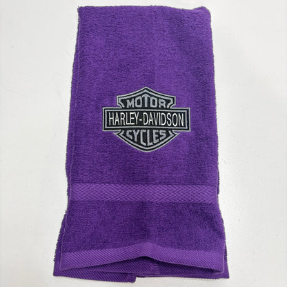 purple towel with an embroidered harley davidson logo in gray thread on it