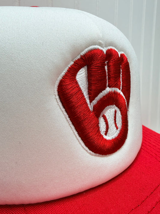 Close-up of a white baseball cap with a red embroidered logo featuring a baseball and a heart shape, with a red side panel visible.