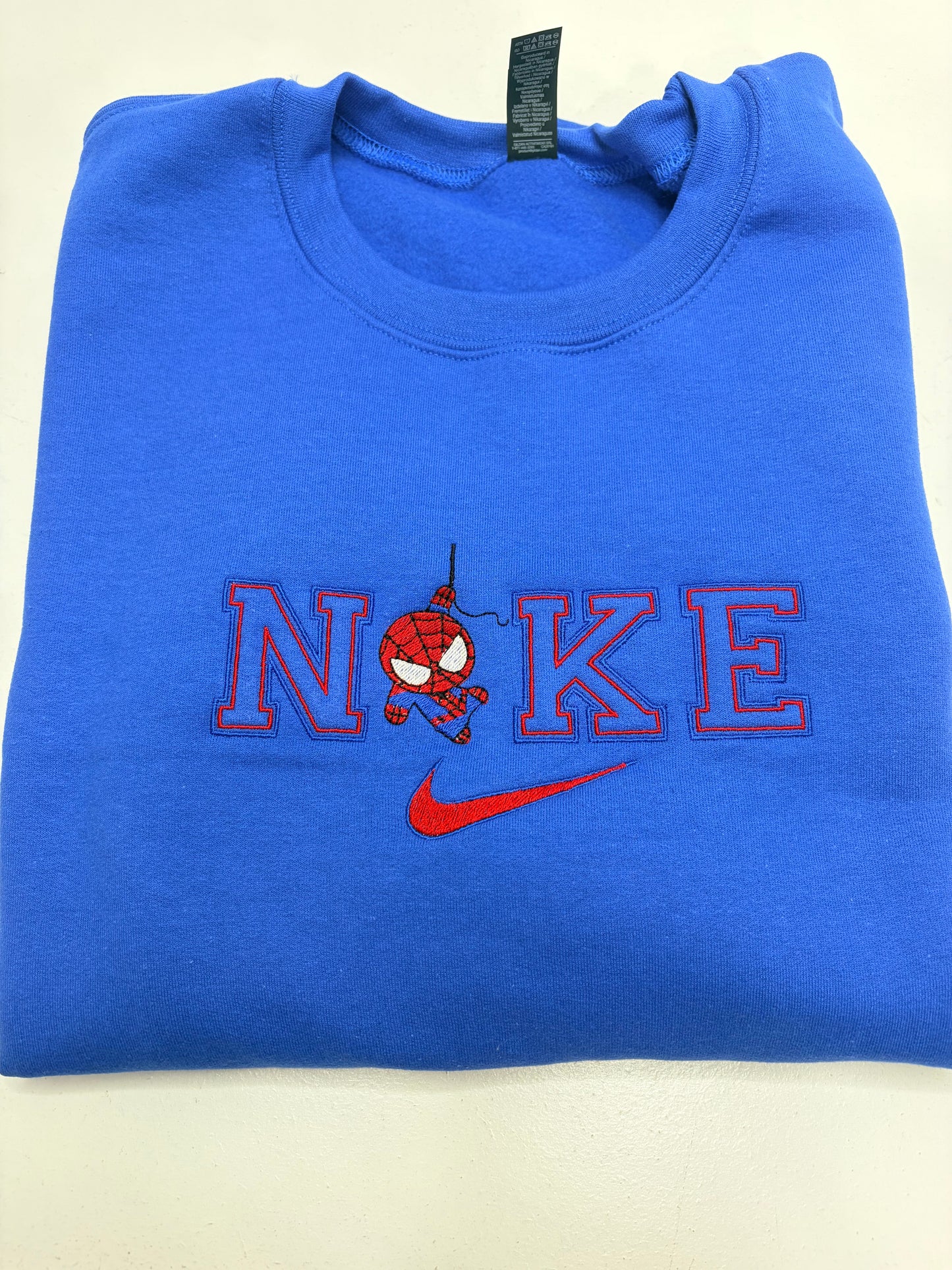 Blue sweatshirt with a red and black design and Nike logo on a beige background