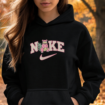 A woman wearing a black hoodie with a pink and white graphic that reads 'NIKE' with a cartoon character and a pink swoosh, set against an autumn outdoor background.