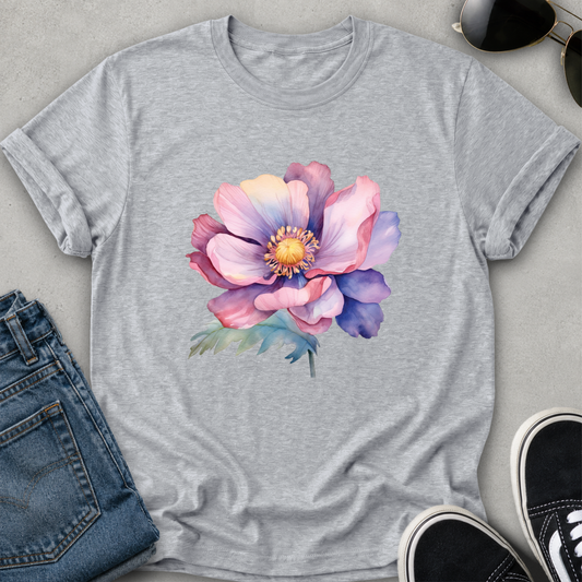 A heather gray short-sleeve crewneck t-shirt featuring a colorful watercolor-style graphic of a large pink and purple flower with a yellow center on the chest, displayed against a light gray background.
